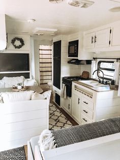 a kitchen and living room in an rv with white cabinets, black counter tops, and rugs