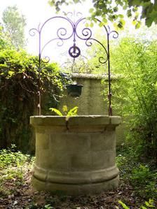 an old stone fountain in the middle of a garden with plants growing out of it