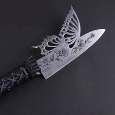 a knife that is on top of a black surface with roses and butterflies on it