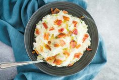 a black bowl filled with mashed potatoes and bacon on top of a blue towel