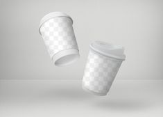 two white coffee cups flying in the air with their lids down and one is empty