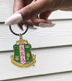 a woman's hand holding a green and pink keychain with the letters aa on it