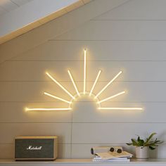 a white fireplace with a neon sunburst on the wall above it next to a radio