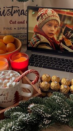 an open laptop computer sitting on top of a desk next to candy and candies