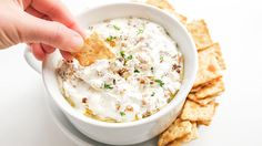 a person dipping crackers into a bowl of dip