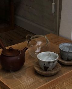 three bowls and a teapot on a wooden table