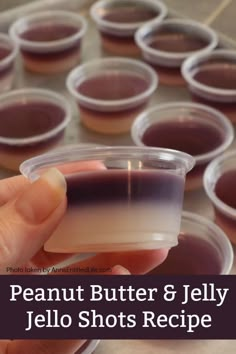 a hand holding a plastic container filled with jello shots and the words, peanut butter & jelly jello shots recipe