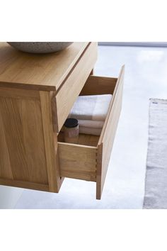 an open drawer in a bathroom next to a rug and bowl on the counter top