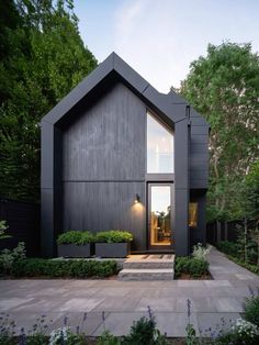 a black house is surrounded by trees and bushes