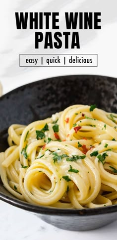 a black bowl filled with pasta and topped with parsley