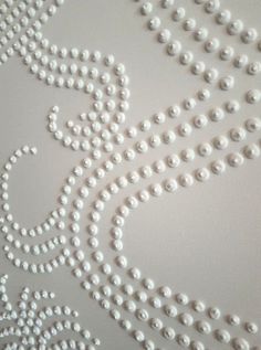 white pearls are arranged on the wall in an intricate pattern, and it looks like they have been beaded together