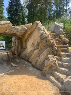 a wooden bench sitting in front of a rock formation with stairs leading up to it