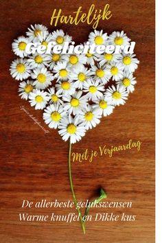 a book cover with daisies in the shape of a heart on a wooden surface