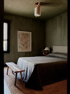 a bed sitting in a bedroom next to a wooden table and lamp on top of a hard wood floor