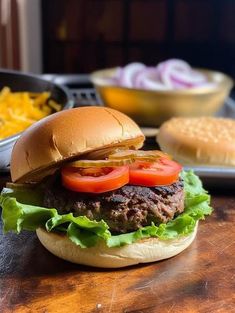 a hamburger with lettuce, tomato and onion on it sitting on a wooden table