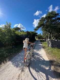 a woman riding a bike down a dirt road