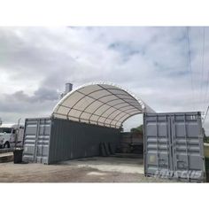 a truck is parked in front of a large metal structure with an awning over it