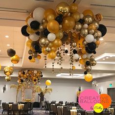 a room filled with tables and chairs covered in gold, black, and white balloons