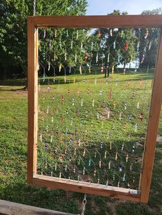 a wooden frame with many different colored beads hanging from it's sides in the grass