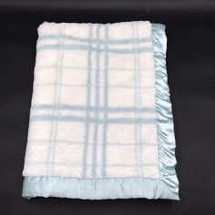 a white and blue blanket on top of a black table with a light blue border