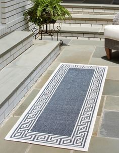 a blue and white rug sitting on top of a stone floor next to a chair