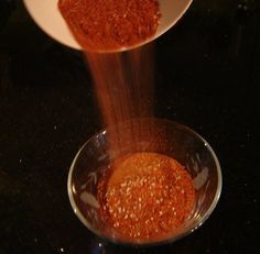 two bowls filled with spices on top of a black counter