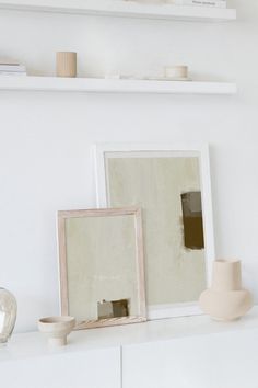 two white vases sitting on top of a white shelf next to a mirror and other items