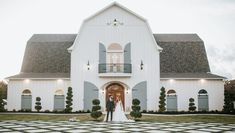 a bride and groom standing in front of a white church