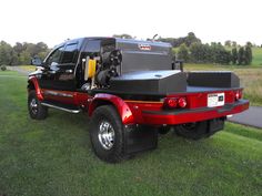 a red truck parked on top of a lush green field