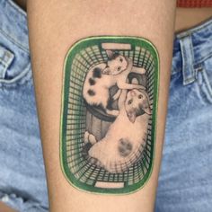 a person with a tattoo on their arm has a picture of two cats in a basket