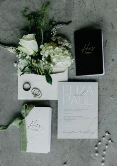 the wedding stationery is laid out on the floor with flowers and rings next to it