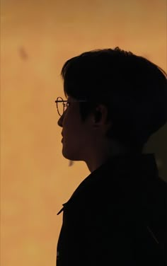 the silhouette of a person wearing glasses in front of an orange sky with no clouds