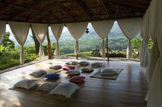 a room with lots of pillows on the floor and curtains hanging from the ceiling over it