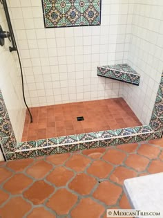 a bathroom with tiled flooring and tile shower stall in the corner, next to a bench