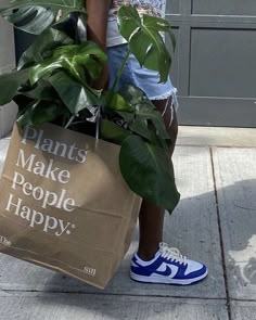 a woman carrying a bag with plants in it