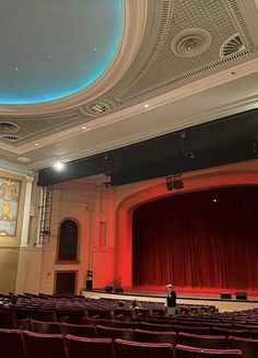 an empty auditorium with red seats and a blue ceiling