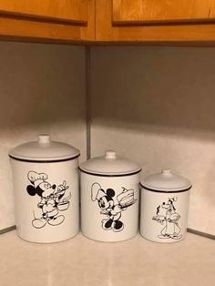 three mickey mouse canisters are on the counter