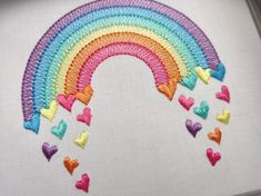 an embroidered rainbow with hearts on it