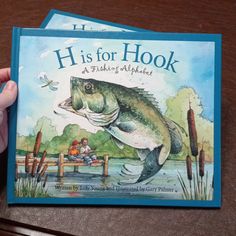 two children's books about fishing are being held up to the camera by their hands