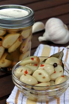 a glass jar filled with pickled onions on top of a table next to garlic