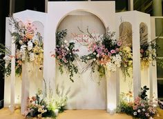 an outdoor wedding setup with flowers and greenery on the wall, surrounded by white pillars