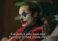 the joker is sitting down with his face painted like a clown and has a quote on it