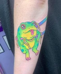 a colorful frog tattoo on the left forearm and right arm, with an arrow in it's mouth