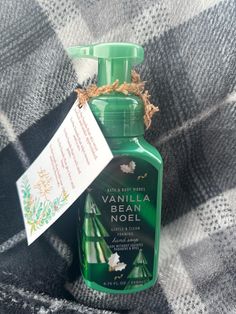 a bottle of vanilla foaming next to a tag on a plaid blanket with an ornament