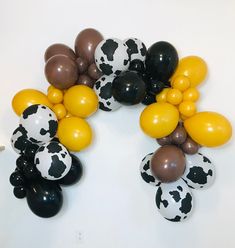 black, white and brown balloons are arranged in the shape of a cow print wreath