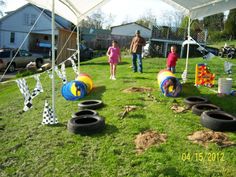 kids playing in an obstacle course at a backyard party with giant tires and balls on the grass