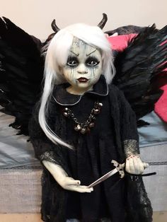 a doll with white hair and black makeup holding a knife