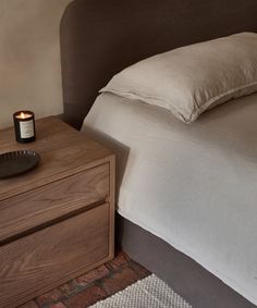 a bedroom with a bed, night stand and candle on the nightstand next to it