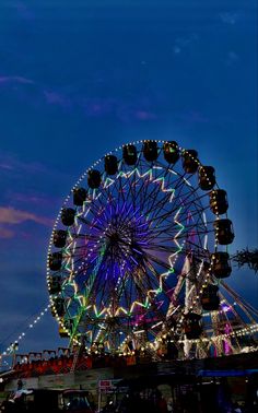 a ferris wheel lit up at night with lights on it's sides and the sky in the background