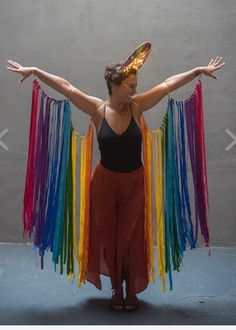 a woman with her arms spread out in front of the camera, wearing a rainbow colored dress